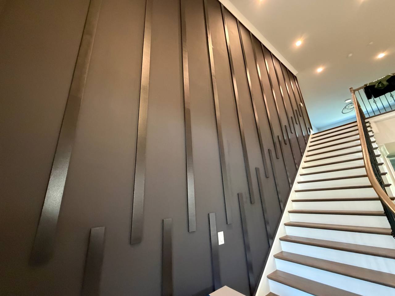 Custom accent wall with vertical metal strips along staircase